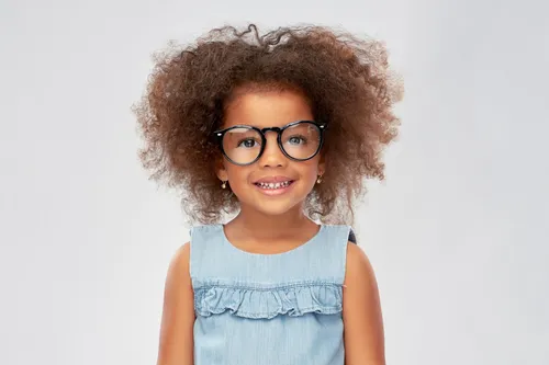 Une petite fille sourit avec ses lunettes de vue rondes