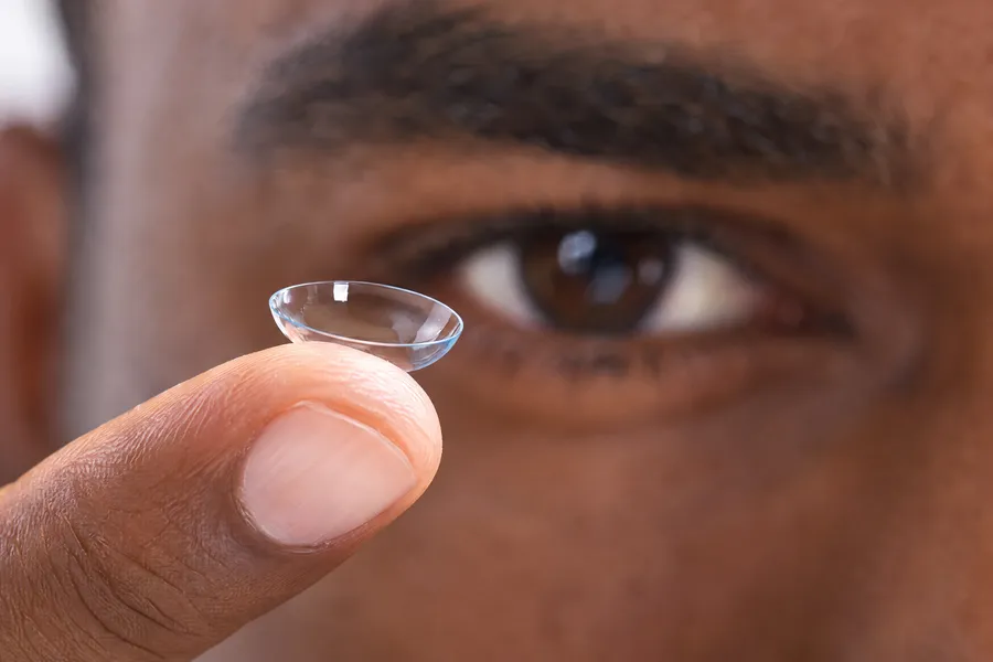 Une lentille de contact sur le bout du doigt, devant l’œil